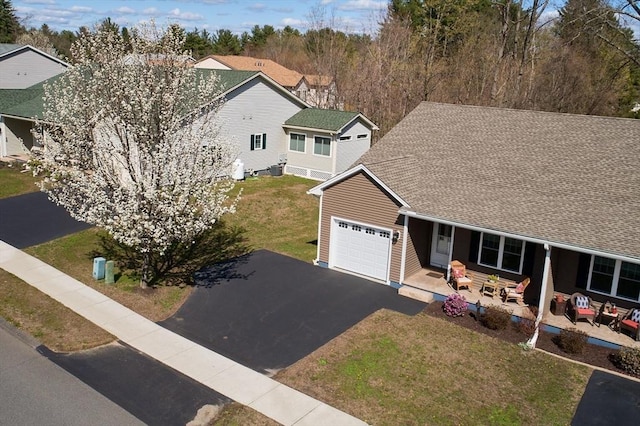 view of front of property featuring a garage, a front yard, roof with shingles, and driveway