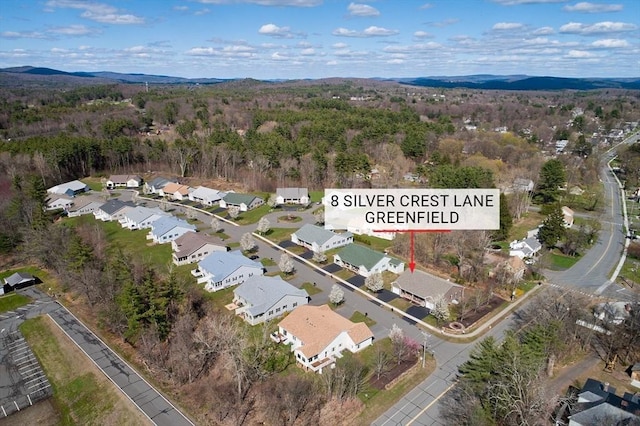 drone / aerial view featuring a residential view, a mountain view, and a wooded view