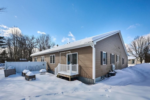 snow covered house featuring fence