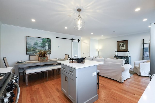 kitchen featuring a kitchen island, light hardwood / wood-style floors, hanging light fixtures, gray cabinets, and a barn door