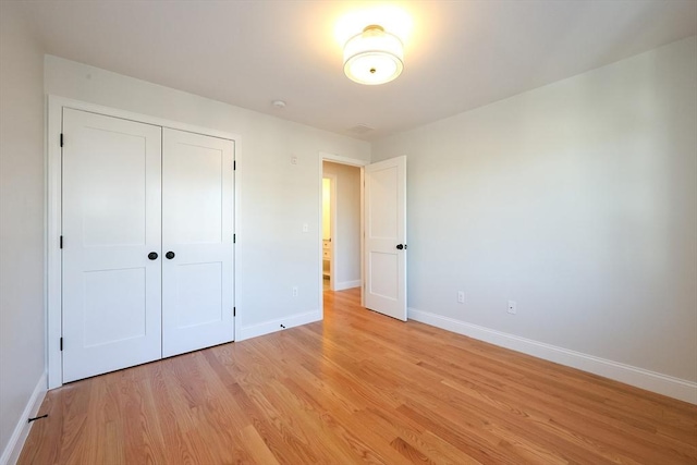 unfurnished bedroom featuring light wood-type flooring and a closet