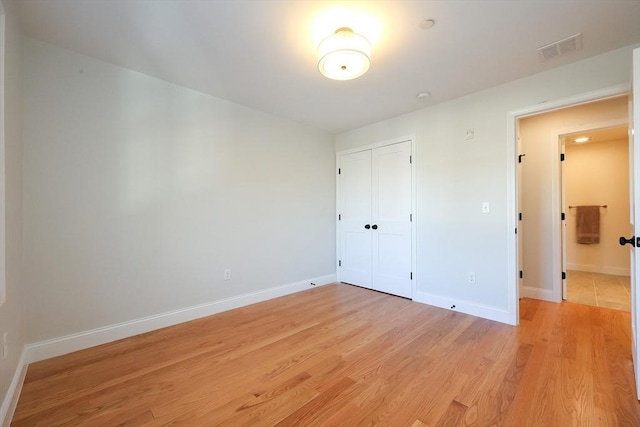 unfurnished bedroom with light hardwood / wood-style flooring and a closet