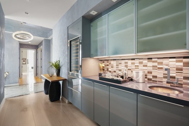 kitchen with sink, backsplash, and light hardwood / wood-style floors