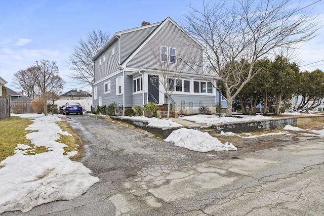 colonial inspired home with aphalt driveway and a chimney