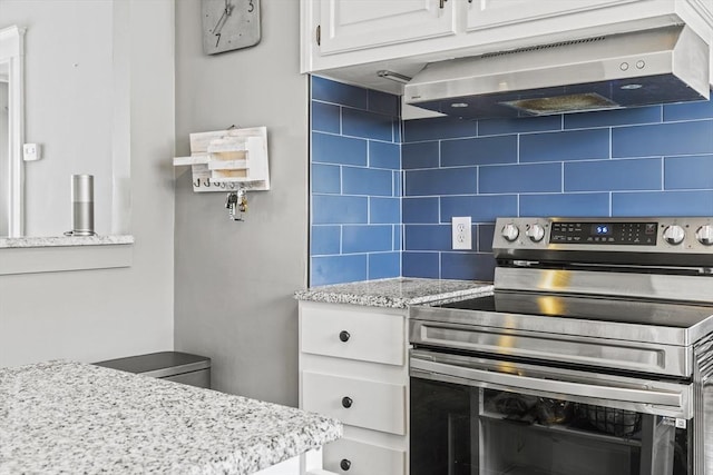 kitchen with exhaust hood, white cabinets, stainless steel electric range, light stone countertops, and tasteful backsplash