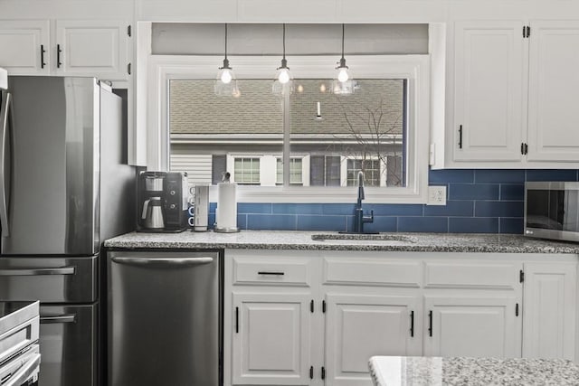 kitchen with pendant lighting, tasteful backsplash, freestanding refrigerator, white cabinetry, and a sink