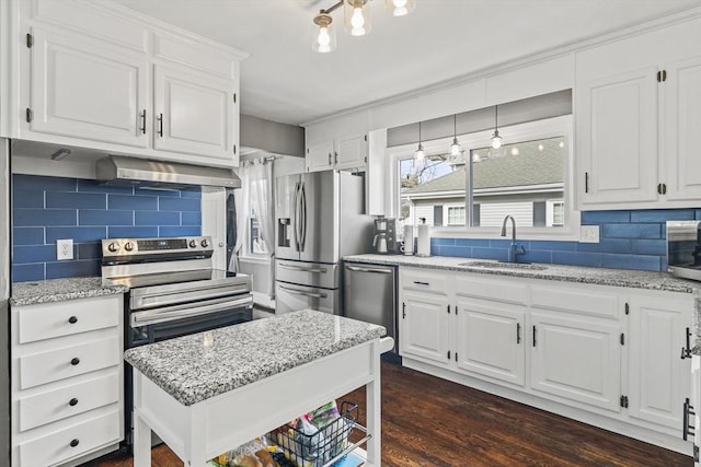 kitchen featuring light stone counters, stainless steel appliances, white cabinetry, a sink, and wall chimney range hood