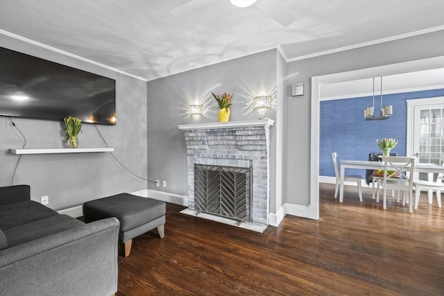 living room featuring dark wood-type flooring, a fireplace, crown molding, and baseboards