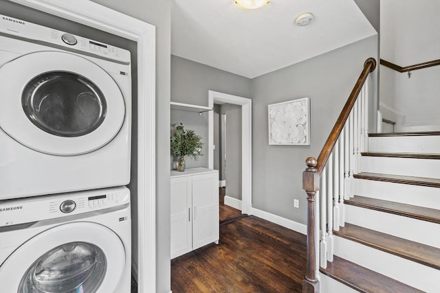 laundry area featuring dark wood-style floors, stacked washer / drying machine, laundry area, and baseboards