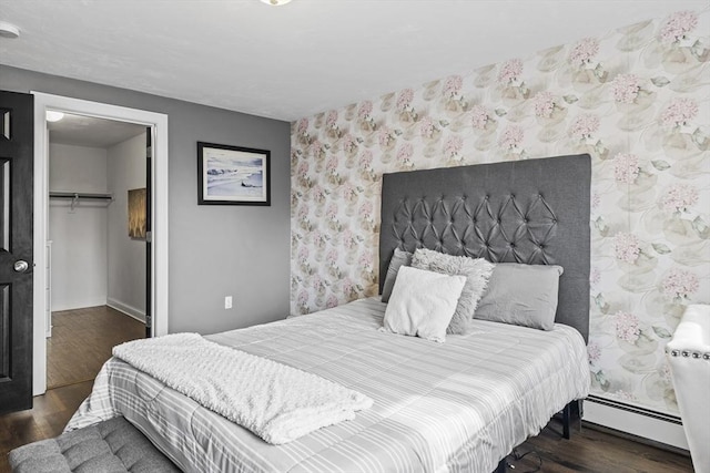 bedroom with dark wood-style flooring, a spacious closet, a closet, and wallpapered walls