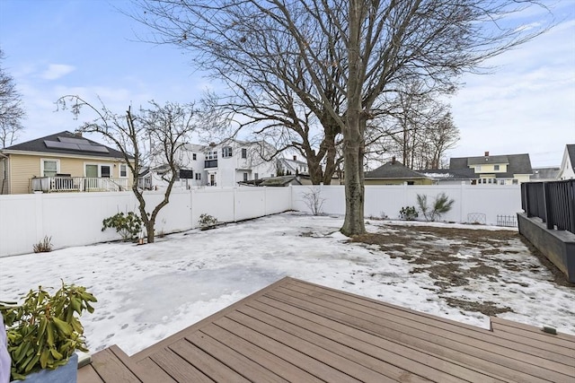 snow covered deck featuring a residential view and a fenced backyard