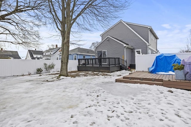 snow covered property with a fenced backyard and a wooden deck