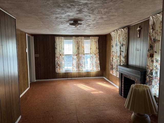 unfurnished living room featuring carpet flooring, a textured ceiling, and wood walls