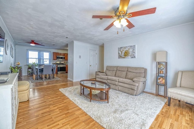 living room with ceiling fan, light wood-type flooring, and ornamental molding