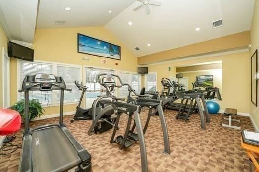 gym featuring ceiling fan, light colored carpet, and lofted ceiling