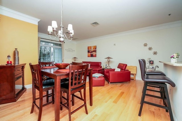 dining area featuring an inviting chandelier, ornamental molding, and light hardwood / wood-style floors