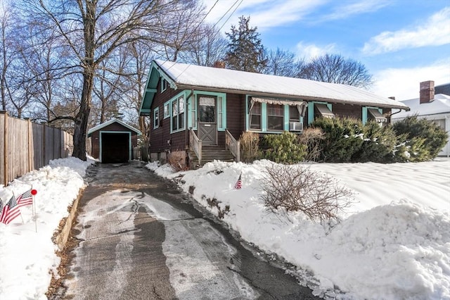 view of front of property featuring a garage, driveway, an outdoor structure, and fence