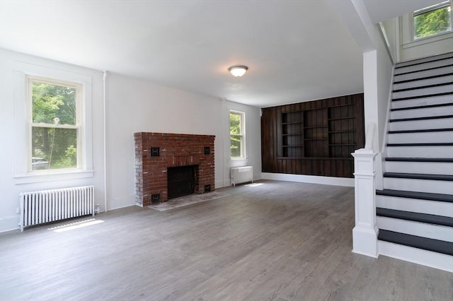 1194 Thorndike St, Palmer, MA 01069 - unfurnished living room with radiator, radiator heating unit, stairway, wood finished floors, and a fireplace
