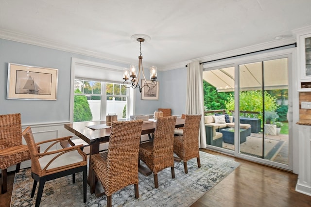 dining space with crown molding, hardwood / wood-style flooring, and an inviting chandelier