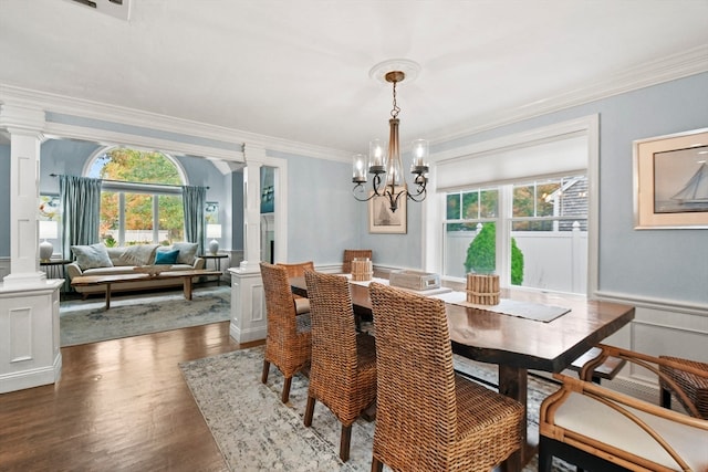 dining space with ornamental molding, a wealth of natural light, an inviting chandelier, and dark hardwood / wood-style flooring