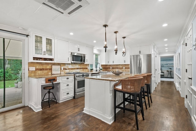 kitchen featuring appliances with stainless steel finishes, light stone countertops, a kitchen island, and pendant lighting