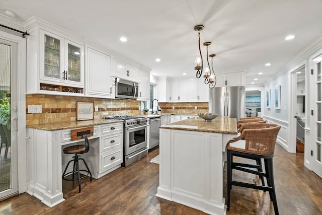 kitchen featuring white cabinets, a kitchen island, light stone countertops, dark hardwood / wood-style floors, and stainless steel appliances