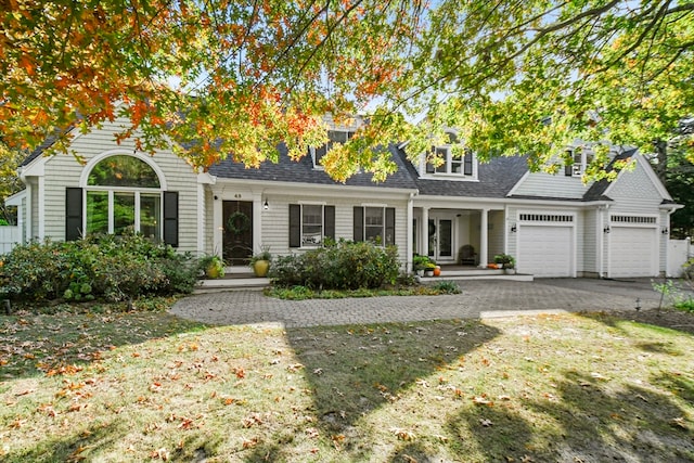 view of front of property featuring covered porch, a front lawn, and a garage