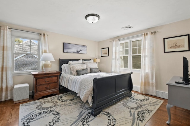 bedroom featuring a baseboard heating unit and wood-type flooring