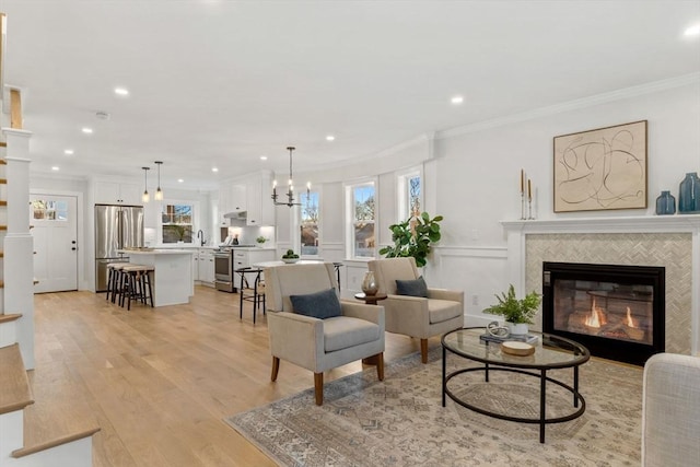 living room with sink, light hardwood / wood-style flooring, ornamental molding, and a fireplace