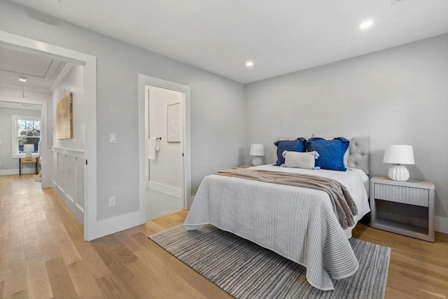 bedroom with light hardwood / wood-style floors, ensuite bath, and ornamental molding