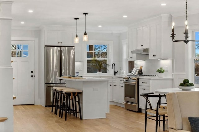 kitchen with decorative light fixtures, white cabinets, a center island, a breakfast bar area, and stainless steel appliances