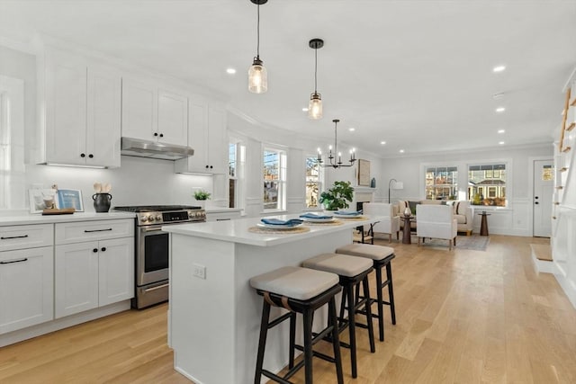 kitchen featuring pendant lighting, white cabinetry, gas stove, and ornamental molding