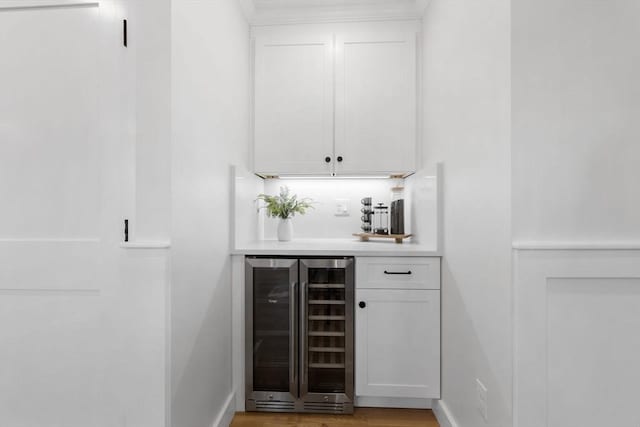 bar with white cabinets, light hardwood / wood-style floors, and wine cooler