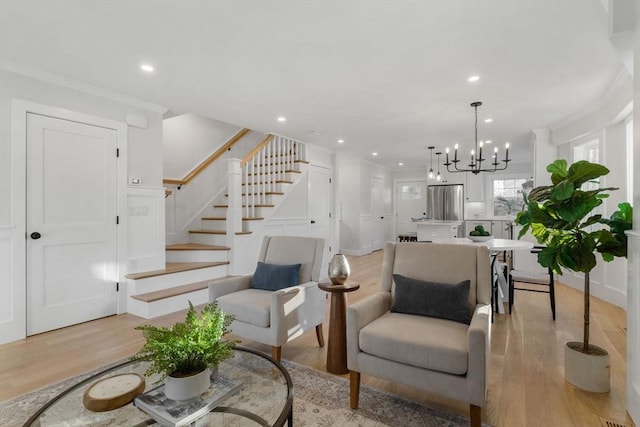 living room with light wood-type flooring, crown molding, and a notable chandelier