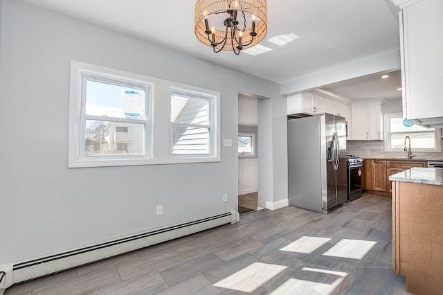 kitchen featuring backsplash, a baseboard heating unit, stainless steel refrigerator with ice dispenser, a notable chandelier, and gas stove