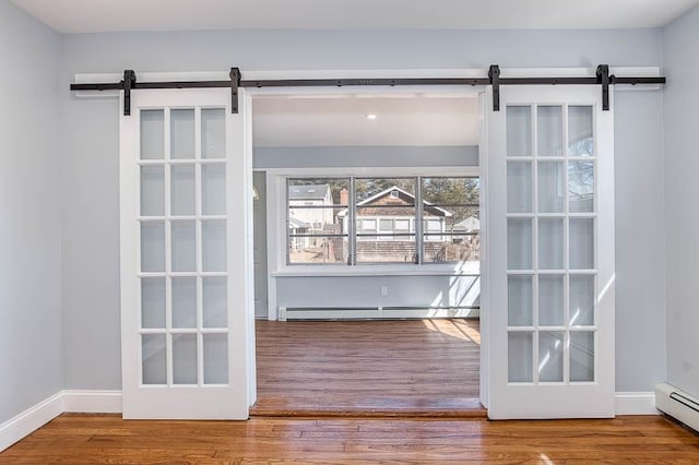 doorway featuring a barn door, baseboard heating, and wood finished floors