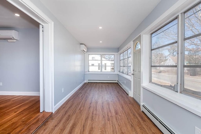 unfurnished sunroom with a baseboard heating unit and a wall mounted air conditioner