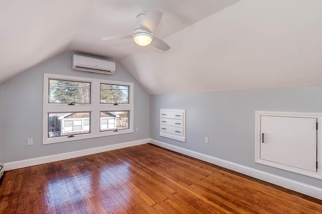 additional living space with baseboards, lofted ceiling, wood-type flooring, ceiling fan, and a wall mounted air conditioner