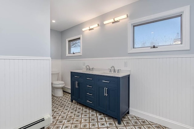 bathroom with toilet, a baseboard radiator, a sink, and wainscoting