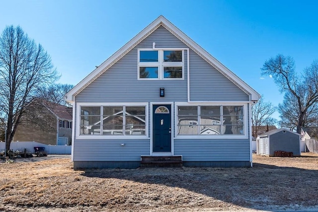 bungalow featuring a storage unit, entry steps, a sunroom, fence, and an outdoor structure