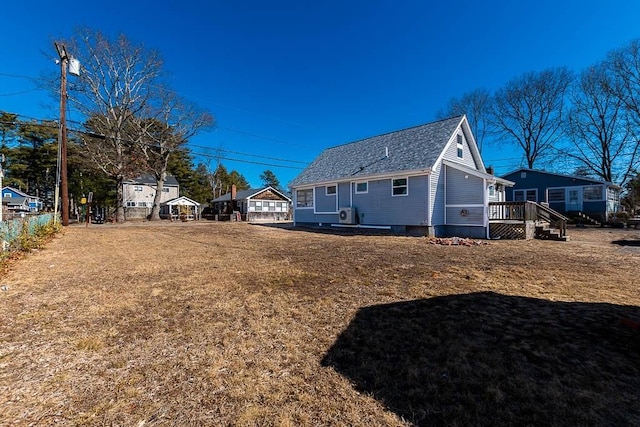 view of side of property featuring a shingled roof and a wooden deck