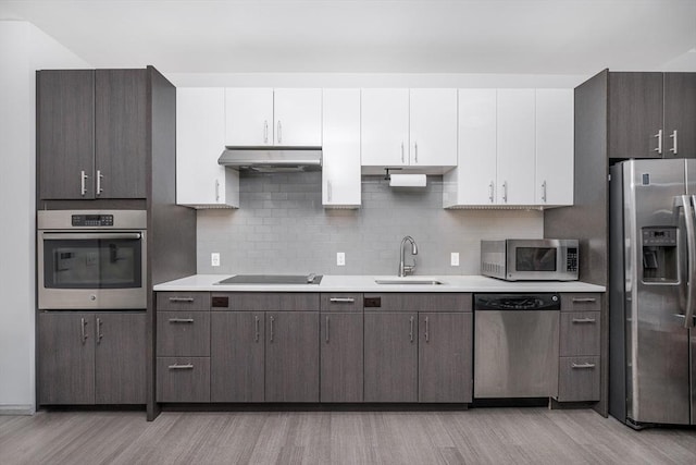 kitchen with stainless steel appliances, tasteful backsplash, sink, and white cabinets