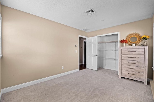 unfurnished bedroom with light colored carpet, a closet, and a textured ceiling