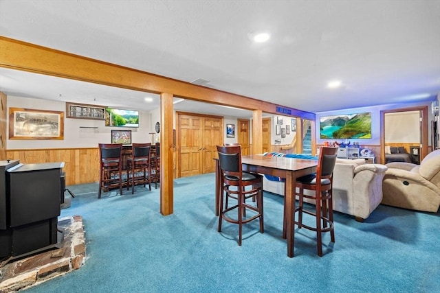 dining room with carpet floors and wood walls