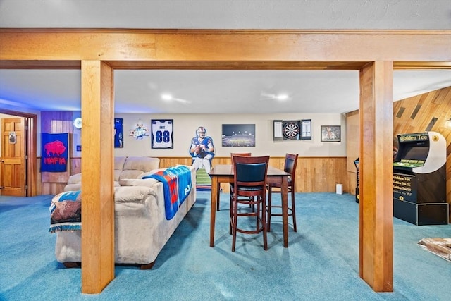 carpeted dining area featuring wood walls