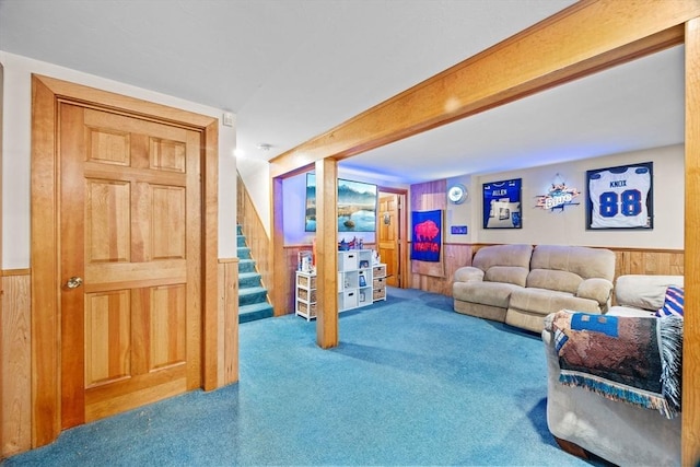 carpeted living room with beam ceiling and wood walls