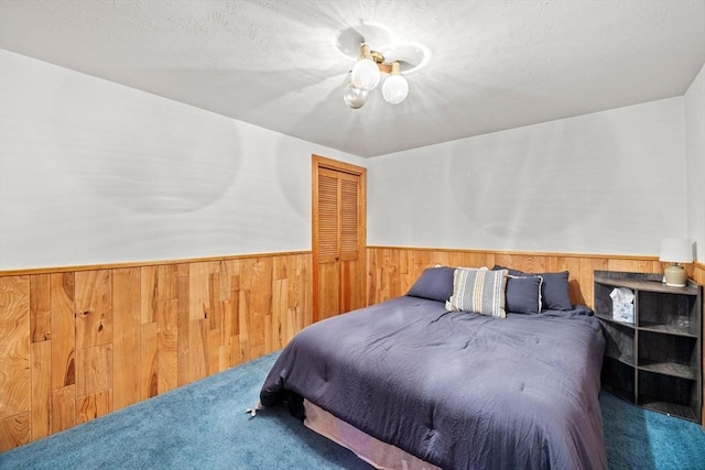 bedroom featuring wooden walls, a closet, and carpet flooring