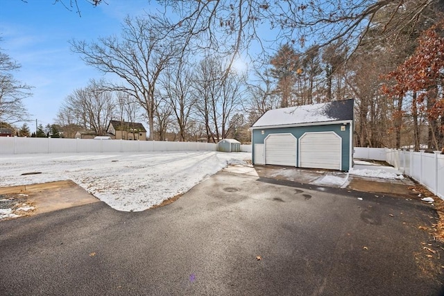 yard layered in snow with a garage and an outdoor structure