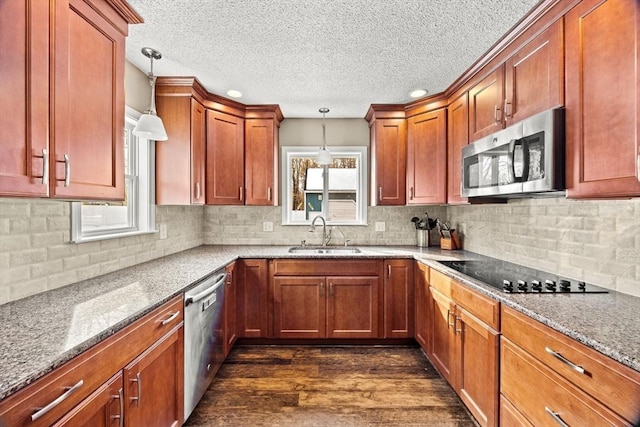 kitchen with light stone countertops, appliances with stainless steel finishes, sink, and pendant lighting