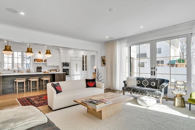 living area featuring recessed lighting, light wood-style flooring, french doors, and crown molding